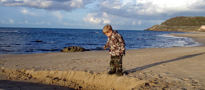 Joshua playing in the sand at the beach at Lu Bagnu