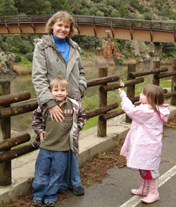 Mandy poses with the kids in front of a bridge across the river