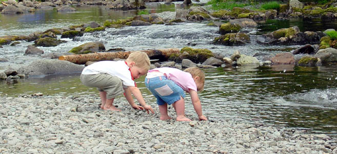 Joshua and Misha throwing stones into a river near Millom
